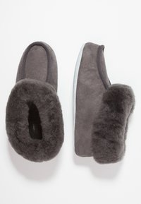 Pantofole in suede grigio con foderatura in pelliccia soffice, forma arrotondata e suola in gomma grigio chiaro. Texture morbida e design senza cuciture con aperture elastiche.