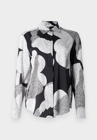 Camicia a maniche lunghe in bianco e nero, caratterizzata da un motivo geometrico con forme e texture variabili. Chiusura frontale con bottoni e colletto.