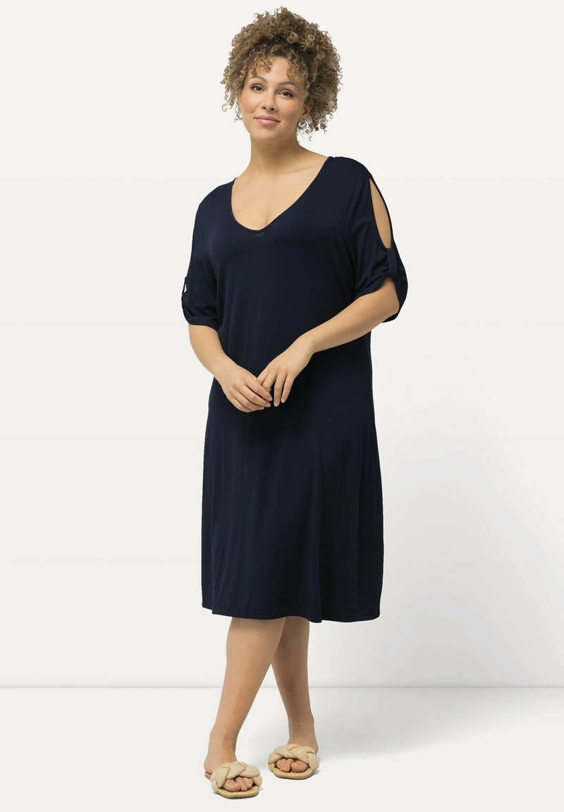 Vestito blu navy, di lunghezza al ginocchio, con maniche corte e dettaglio spalle scoperte, realizzato in un tessuto morbido e leggero. Tessuto liscio, vestibilità comoda.