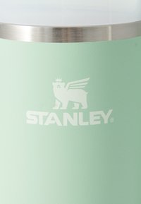 Tazza in acciaio inossidabile verde con una finitura opaca liscia e un bordo argentato. Presenta un logo in rilievo bianco di un leone con ali.
