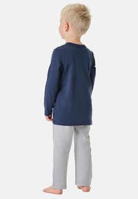 Marineblaue Langarmshirt und hellgraue Hose aus weichem Material, mit einem schlichten Design und lässiger Passform. Sichtbares Logo auf der Seite des Shirts.
