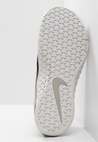 Nike kengät pohjan näkymä, jossa on teksturoitu valkoinen kumimateriaali, jossa on timanttikuvio ja voimakas harmaa swoosh-logo.