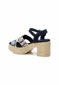 Sandaña de ante azul marino con bordado floral en la parte superior, correa trasera cerrada y un tacón grueso de cuerda trenzada.