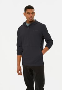 Pullover grigio scuro con cappuccio e design a mezza zip, dotato di una texture morbida e di una tasca frontale. Logo VAUDE visibile sul petto.