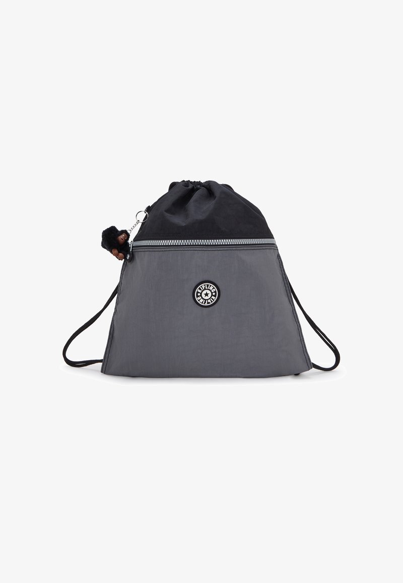 Snoresrygsæk i grå og sort nylon, med en metallisk lynlås og en lille abe-nøglering fastgjort til lynlåsens træk.