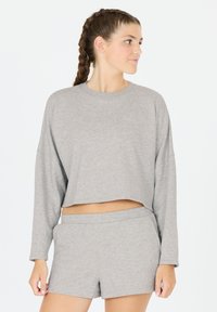 Grijze cropped sweatshirt met lange mouwen, zachte textuur en ronde halslijn, gecombineerd met bijpassende grijze shorts met een elastische tailleband.