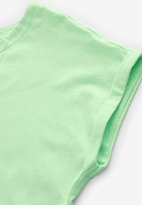 T-shirt en coton vert menthe avec une texture douce, des manches courtes et un col rond. Le tissu semble léger et lisse.