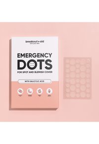Boîte blanche avec du texte noir étiqueté "Emergency Dots" sur un fond rose. Comprend une feuille transparente de patchs ronds pour couvrir les imperfections.