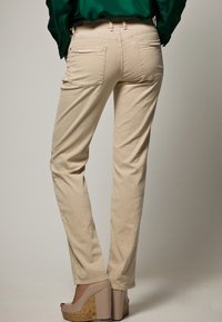 Beiga raka byxor med bakfickor, tillverkade av mjukt tyg. Bärs med tanfärgade plattformsskor med korkklack.