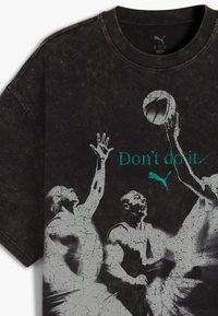 Grafický oversized černý tričko s motivem opotřebovaného vzhledu, bílými siluetami basketbalistů a tyrkysovým textem "Don't do it" spolu s logem Puma.