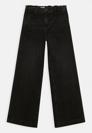 Jeans noirs à jambes larges avec une ceinture élastique haute, poches avant et fermeture à boutons, présentés sur un fond blanc.