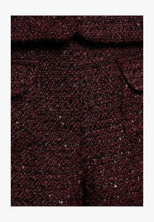 Tessuto marrone scuro con piccole paillettes, caratterizzato da un design strutturato e tasche visibili, creando un aspetto a strati.