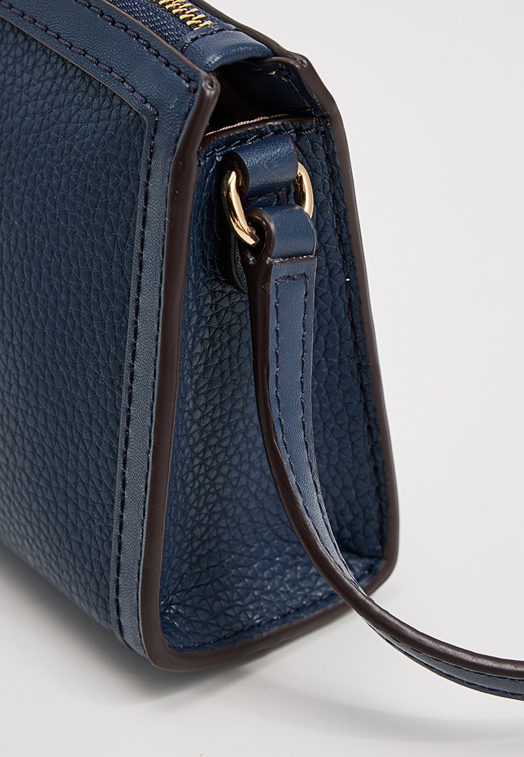 Sac en cuir texturé bleu marine avec une forme structurée, des accents bruns, des éléments en or et une bandoulière amovible pour un transport facile.
