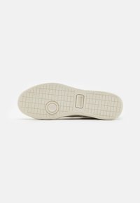 Lacoste sneaker sole, rubber material, beige color, flat design, textured for grip, with circular and rectangular pattern details.