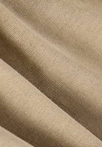 Tissu en coton beige avec un tissage texturé, présentant des plis doux et une surface lisse, mettant en valeur la durabilité et la polyvalence du matériau.