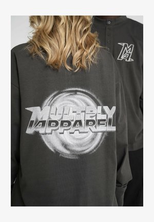 Tmavošedý oversized mikina s nápisom "MULTIPLY APPAREL" v tučnom bielom písme, s vírivým grafickým dizajnom na zadnej strane.