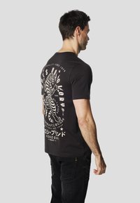Black cotton t-shirt featuring a large white tiger graphic and text on the back. Short sleeves and a crew neck design.