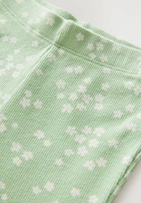 Groene ribstof met witte bloemenpatronen, voorzien van een zachte, textuurachtige afwerking en een elastische tailleband.