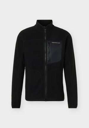 Giacca in pile nera con cerniera frontale completa, collo alto e tasca sul petto con cerniera con marchio "Peak Performance" sul lato destro.