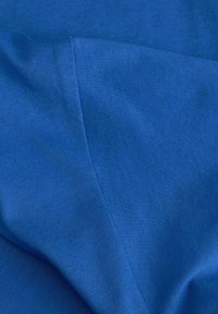 Niebieska tkanina o gładkiej teksturze, z delikatnym połyskiem. Dwa nałożone na siebie kawałki, prezentujące jednolity kolor bez wzorów i widocznych szwów.