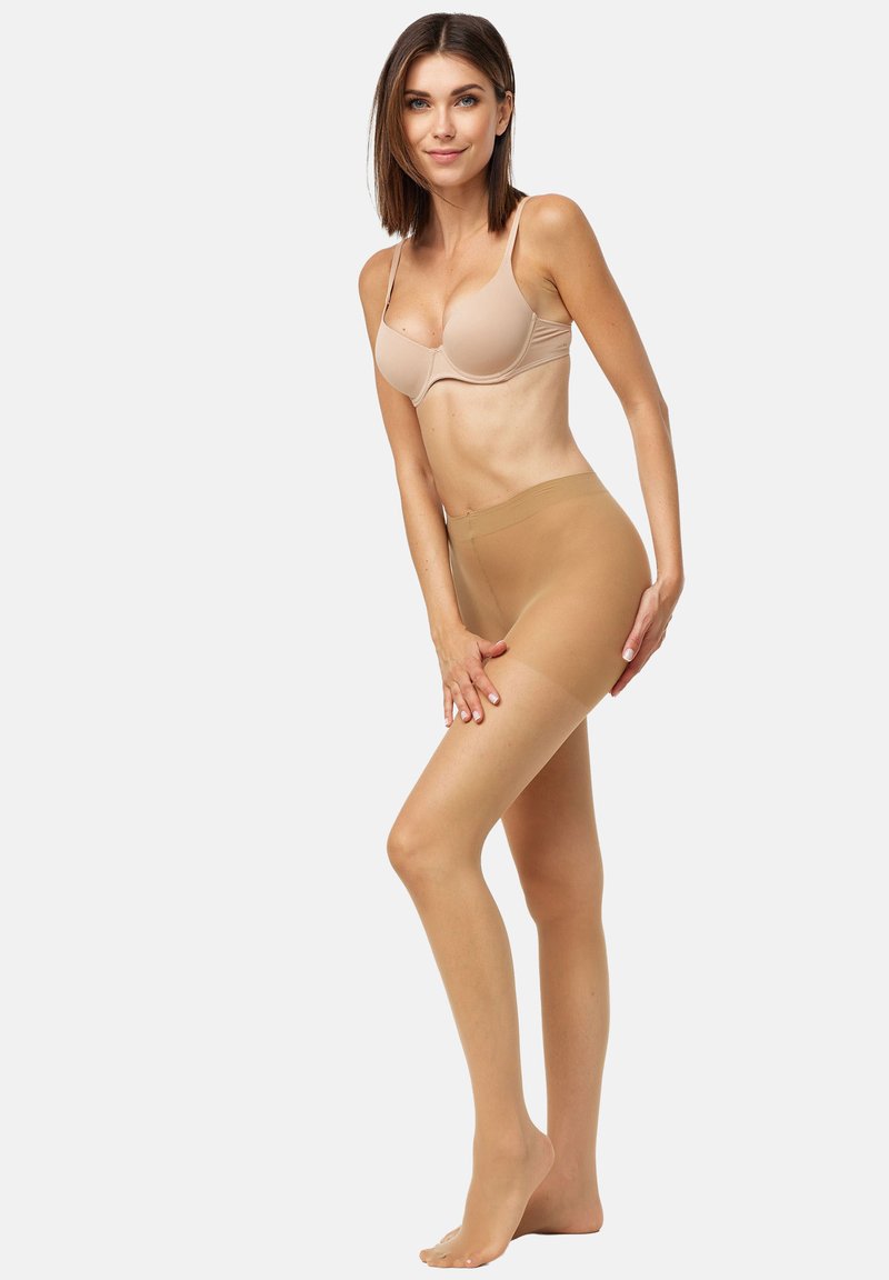 Pantys beiges sin costuras en una modelo, con un acabado mate, cintura alta y una textura suave que realza la forma de las piernas.