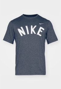 Námořnická modrá Nike tričko s krátkým rukávem, se velkými bílými blokovými písmeny napsanými "NIKE" na přední straně a malým logem na rameni.
