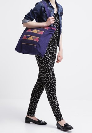 Sac fourre-tout violet avec une broderie à motif géométrique en rose et orange. Design structuré avec des bandoulières épaisses et une texture de tissu douce.