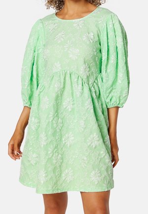 Vestido verde menta con mangas abullonadas tres cuartos y bordado floral en relieve, ajuste holgado con cintura recogida y escote redondo.