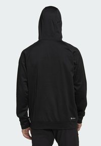 Felpa nera con cappuccio caratterizzata da una texture liscia, vestibilità regolare, maniche raglan e una tasca a marsupio. Include un logo sull'orlo.
