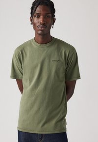 Tricou din bumbac de culoare verde măsliniu, cu mâneci scurte, decolteu rotund și logo-ul subtil Levi's brodat pe piept. Textură netedă, croi lejer.