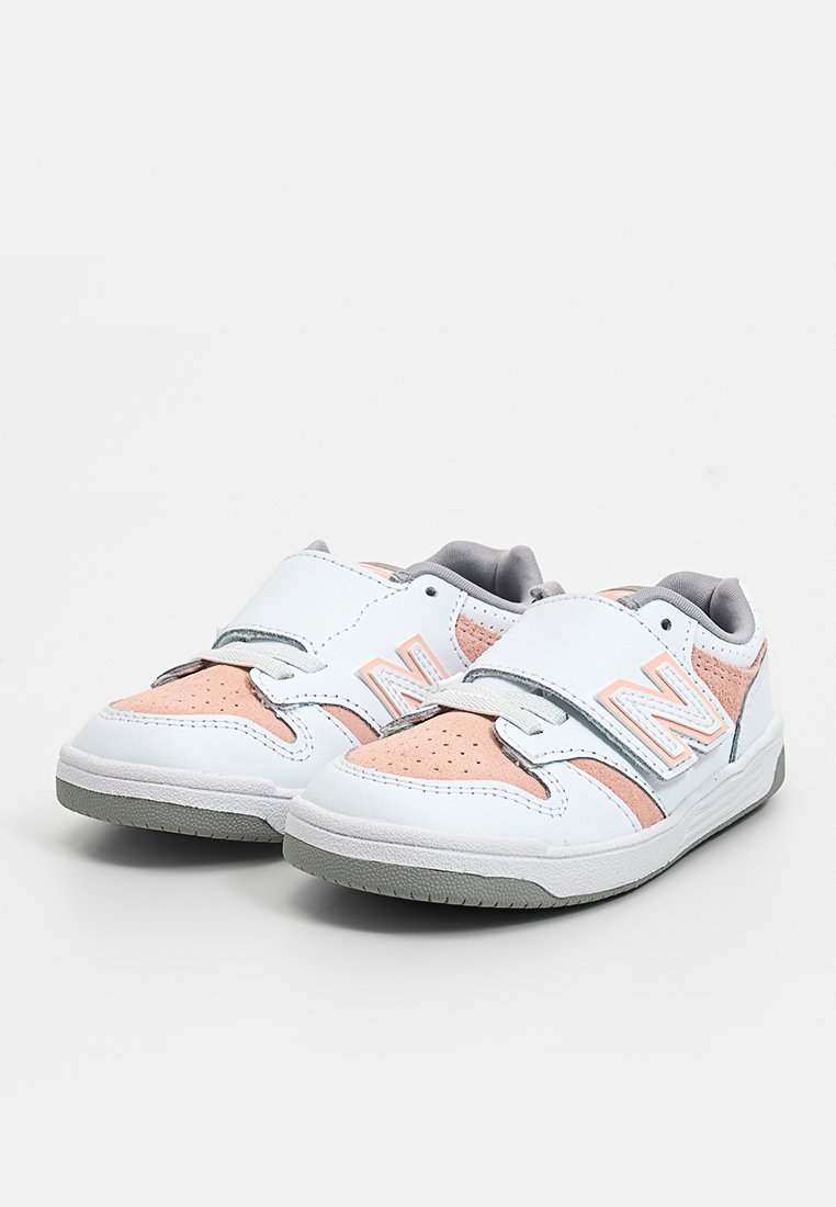 Scarpe sportive bianche con accenti in suede rosa chiaro e dettagli grigi, dotate di una fascia in Velcro e punta perforata per la traspirazione.