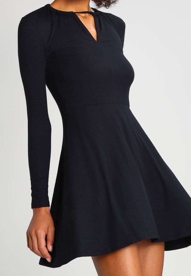 Robe noire à manches longues avec un corsage ajusté et une jupe évasée, présentant un décolleté en trou de serrure et une texture côtelée.
