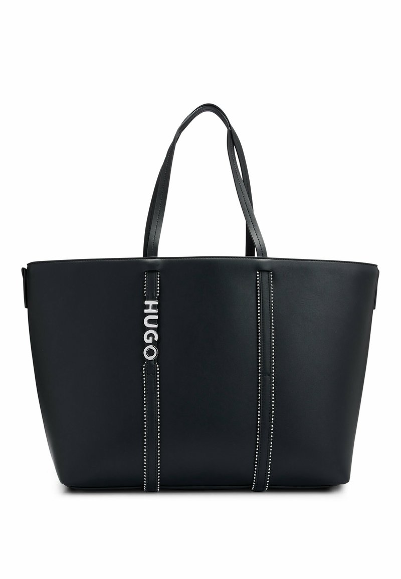 Sac cabas en cuir noir avec deux poignées, rayures verticales cousues, et logo métallique "HUGO" sur la rayure de gauche à l'avant.