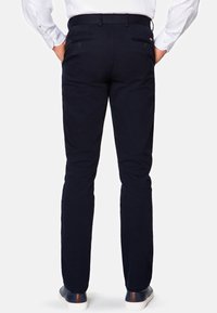 Granatowe spodnie o prostym kroju, wykonane z gładkiego materiału. Posiadają kieszenie tylne z zapięciem na guziki oraz pas z pętelkami na pasek.