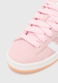 Ρόζ σουέτ αθλητικά παπούτσια με υφασμάτινα κορδόνια, λευκές λεπτομέρειες στο πλάι και μαλακή καουτσούκ σόλα σε ανοιχτό καφέ χρώμα.