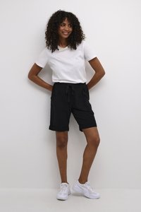 Shorts en jersey noir avec ourlet retroussé et ceinture à cordon, associés à un t-shirt blanc à col rond et des baskets blanches.