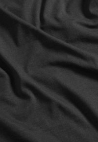 Tessuto di cotone nero con una texture liscia, che mostra onde e pieghe delicate, indicative di un materiale leggero e elastico.
