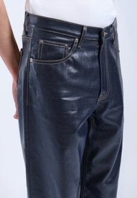 Dark denim jeans with a glossy finish, featuring a slim fit, classic five-pocket design, and contrasting stitching.