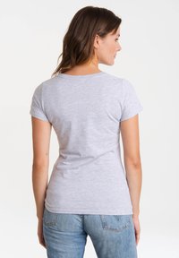 T-shirt gris à manches courtes avec un col rond, un design ajusté et une texture douce, associé à un jean en denim délavé moyen.