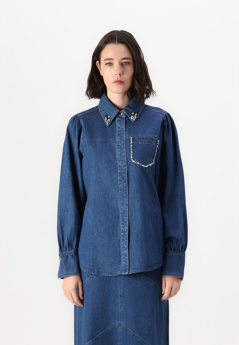 Jeansskjorta med långa ärmar, krage, dekorativa pärlaccent på kragen och en ficka med pärltrim.