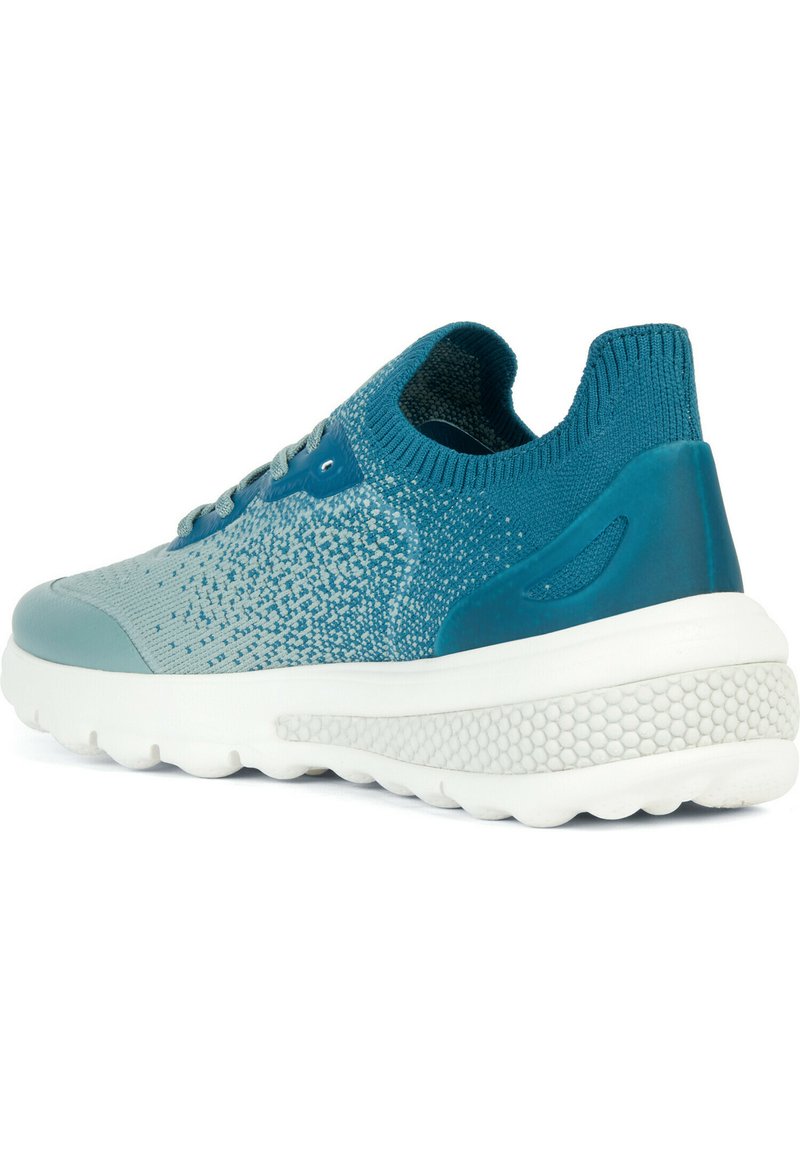 Zapatilla deportiva en color teal con un patrón en degradado, parte superior de tejido texturizado, cuello acolchado y una suela blanca y acolchada con protuberancias.
