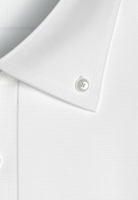 Camicia bianca con colletto realizzata in tessuto texturizzato, con un bottone rotondo con un accento blu sul colletto.