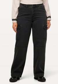 Pantalones cargo de mezclilla negra con piernas anchas, con costuras detalladas y dos bolsillos laterales. El material tiene una textura sutil y un cierre de botón clásico.