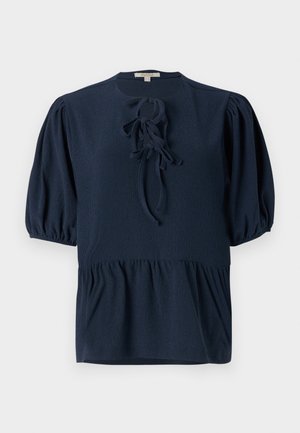 Navy blue short-sleeve blouse with textured fabric, round neckline, and a front tie detail. Peplum cut with gathered puff sleeves.