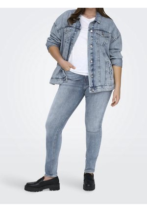 Hellblaues Jeansjackett mit Knopfverschluss über einem weißen Hemd und hellblauen Jeans, kombiniert mit schwarzen Plateauschuhen.