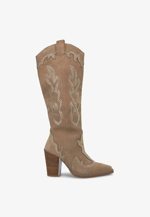 Bottine en suède brun de style western avec bout pointu, couture détaillée et accents cloutés. Elle dispose d'un talon empilé et d'un design décoratif.