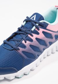 Marinblå och rosa träningssko i mesh och tygmaterial, med en texturerad ovandel, snörning och en vadderad vit sula.