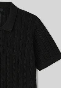 Polo shirt noir en tricot avec une texture côtelée, des manches courtes, un col et une patte de boutonnage à cinq boutons. Design classique, adapté à une tenue décontractée.