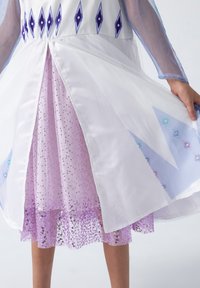 White dress with long sheer sleeves, featuring purple diamond patterns and a layered lavender skirt with sequins.