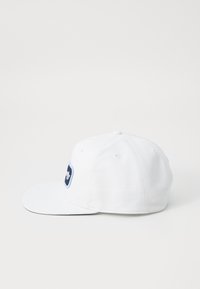 Hvit baseballcaps med flat skjerm og en marineblå logo-lapp på forsiden. Laget av bomull med en glatt tekstur.